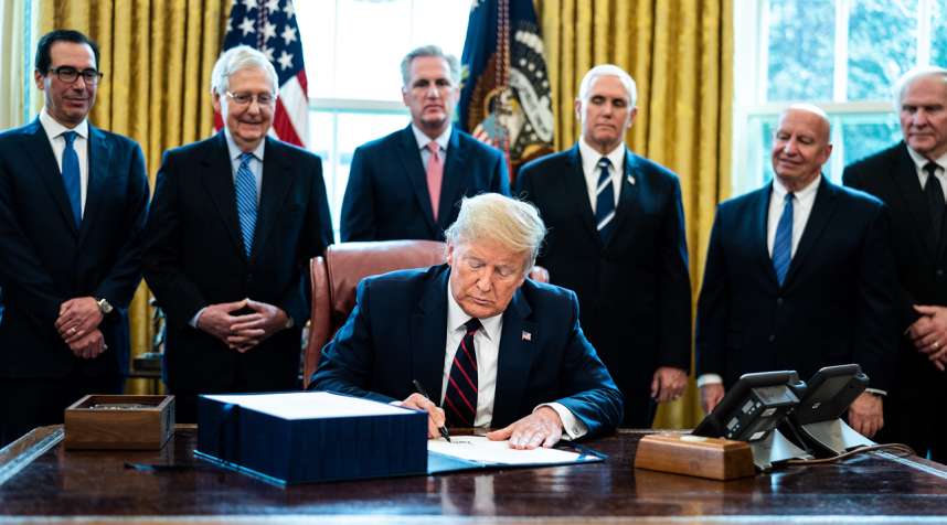 U.S. President Donald Trump signs the CARES Act in the Oval Office of the White House on March 27, 2020.