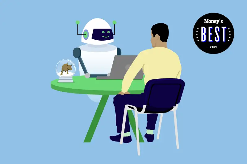 A man sits across a smiling robot using a laptop, there is a snow globe with a bull inside on the table