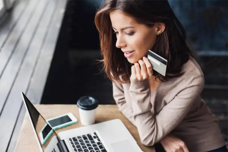 woman staring into her computer holding a credit card