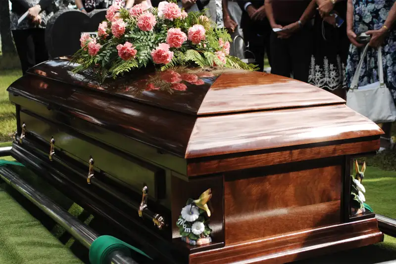 A coffin about to be lowered at a funeral service in a cemetery