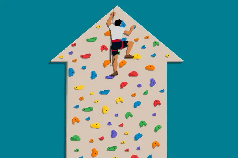 A person climbing to the  peak  of a climbing wall shaped like an upward trending arrow, with no where to go but down