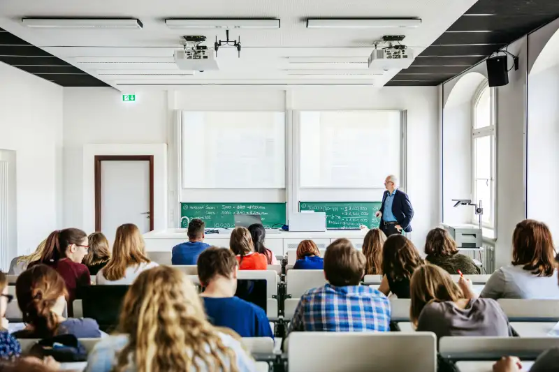 A modern lecture theatre with students listening while the teacher speaks