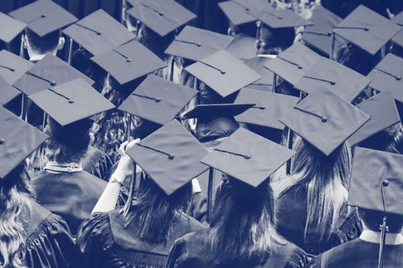 Close-up of multiple rows of students wearing blue graduation caps and robes