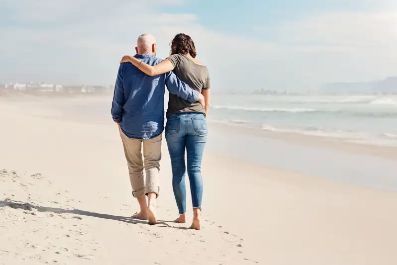 Elderly Father With Adult Daughter Walking Near The Shore