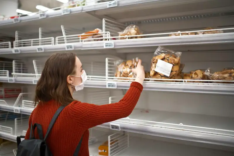 Young woman standing in front of empty shelf in a supermarket