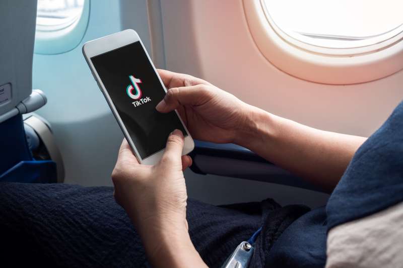 Close-up of a phone with the TikTok app open on an airplane