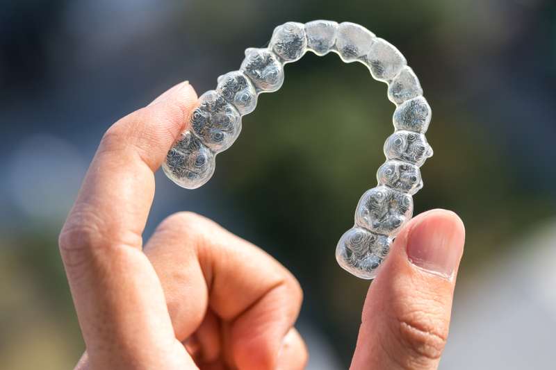 A hand holding Invisalign braces