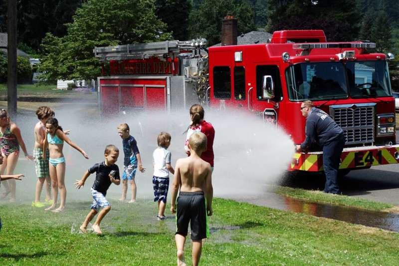 A group of kids play with the water from a fire truck in Camas Washington