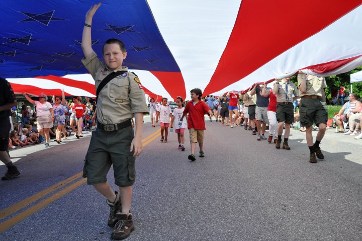 Kids walk under a big United States flag for the 4th of July parade in Severna Park, Maryland
