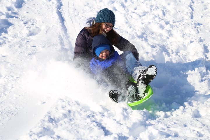 A mother and her son sled down a hill full of snow in Waukee Iowa
