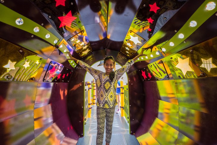 A girl smiles form inside a colorful playground tunnel in Woodbury, Minnesota
