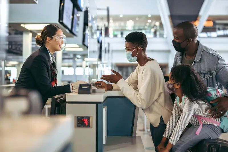 Family of three hand in their passports at the airport check-in desk