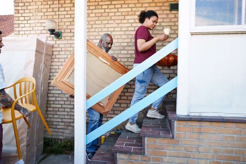 Family carrying various objects while entering their new house