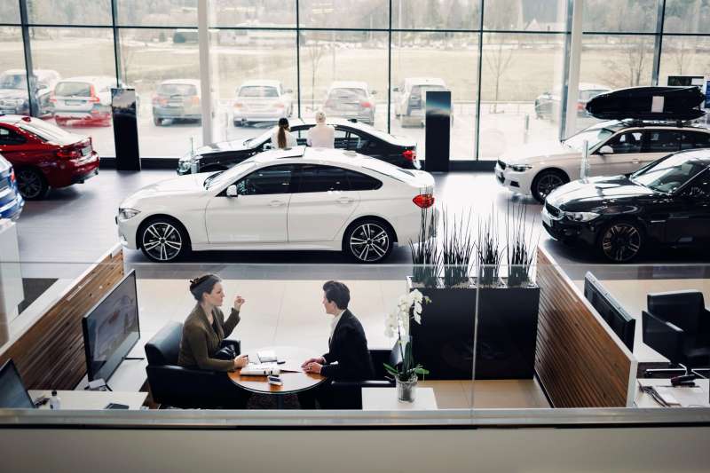High angle view of saleswoman and customer going over paperwork in a car dealership