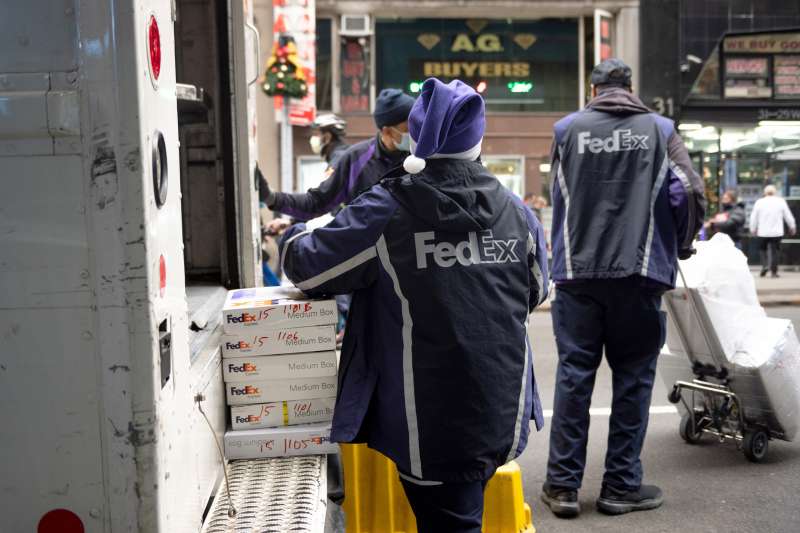 A Fedex employee wearing a Santa Claus hat takes packages off a truck in New York City