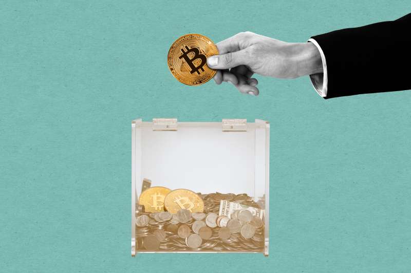 Donation box with money and bitcoins inside. A hand of a man in a suit is near to donate a bitcoin.