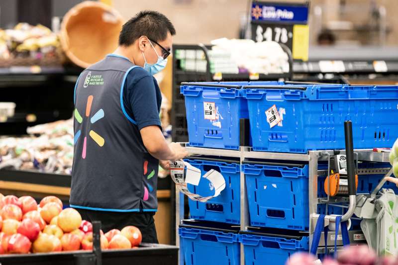 A Walmart employee restocks fruit and vegetables at a Walmart Supercenter