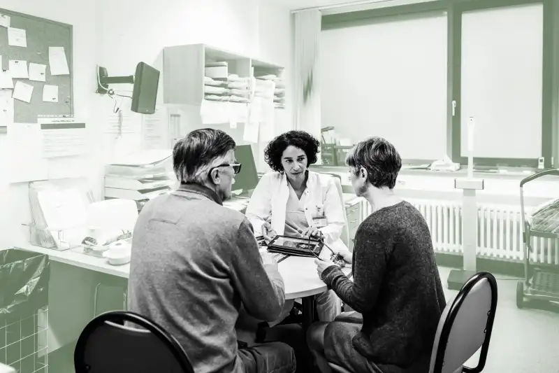 Doctor talking to a senior couple in her office at the hospital.