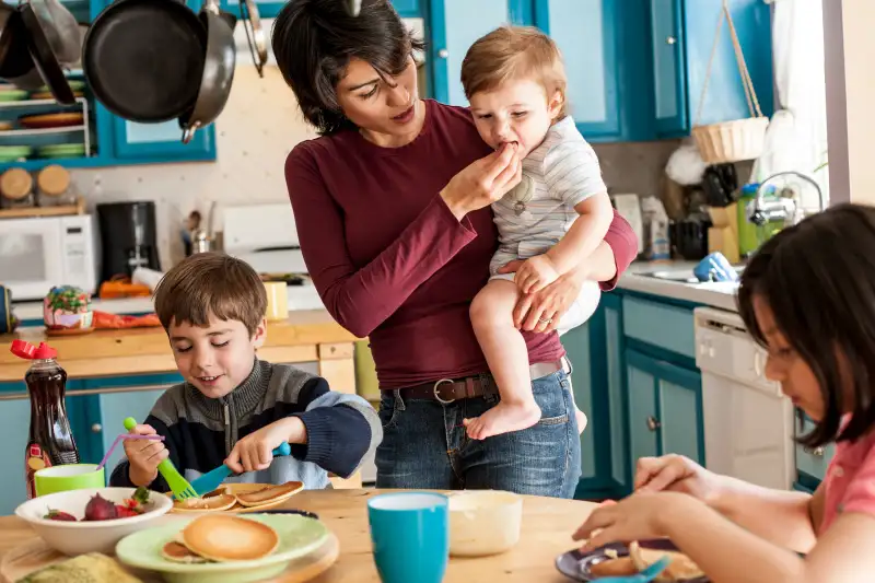 Mother preparing breakfast for her three children