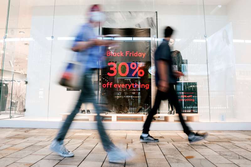 Black Friday shoppers walk past a 30% discount sign in front of a store
