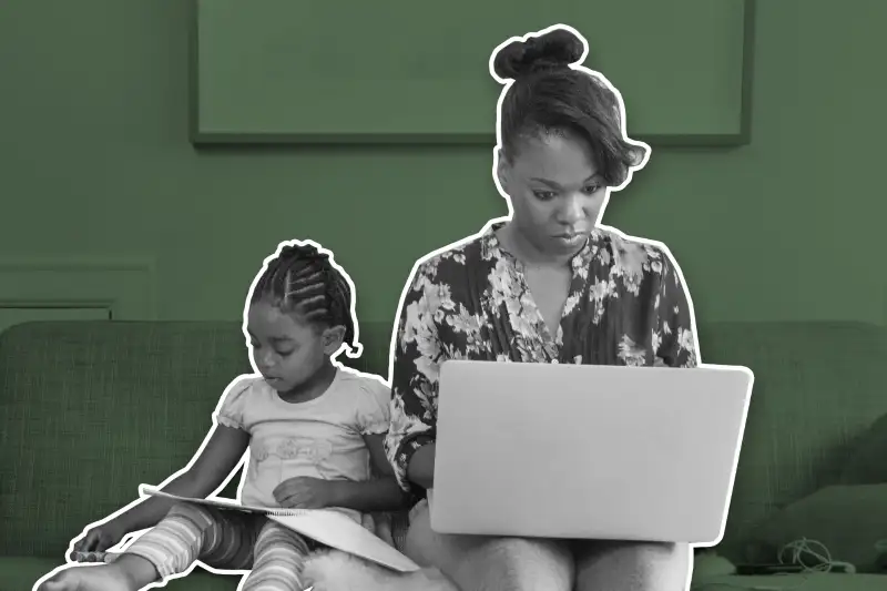 Mother Using Laptop With Daughter Sitting Beside Her