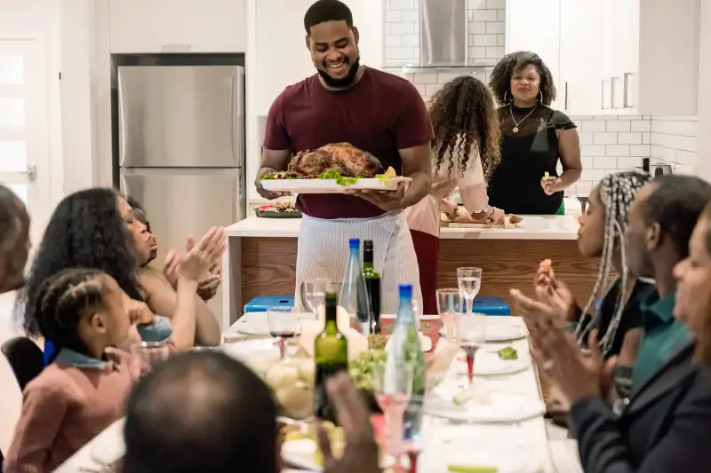 A large family gathers around the dining room table to eat Thanksgiving dinner.