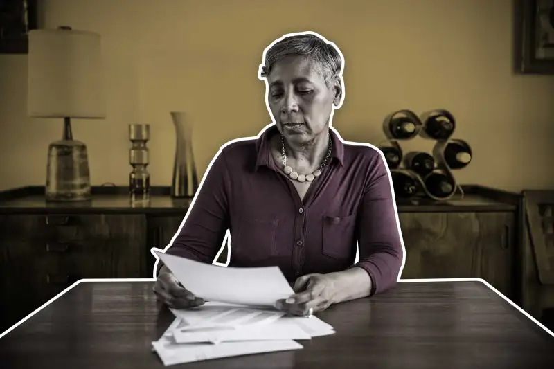 Woman At Home Sitting At Table While Looking At Paperwork