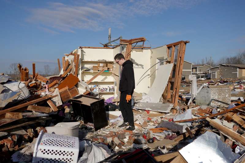 Young boy searches for valuables in the wreckage of a home after it was destroyed by a tornado on December 14, 2021 in Kentucky