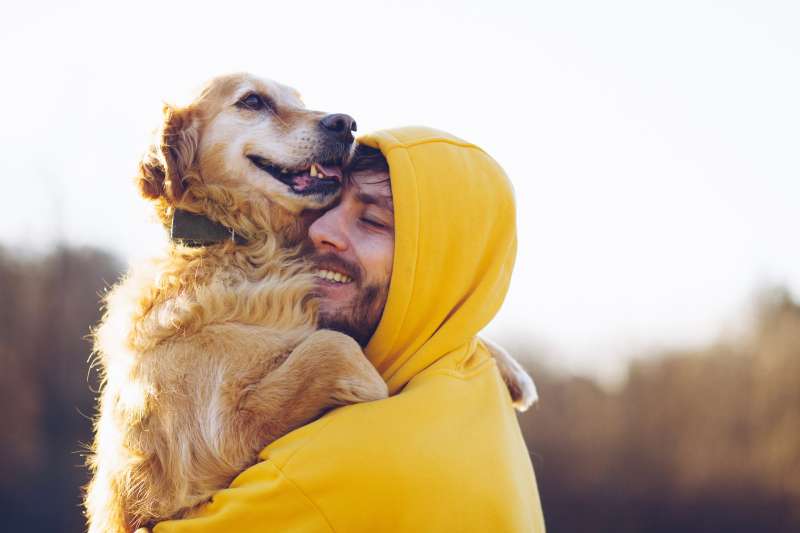 Young man happily hugs his dog