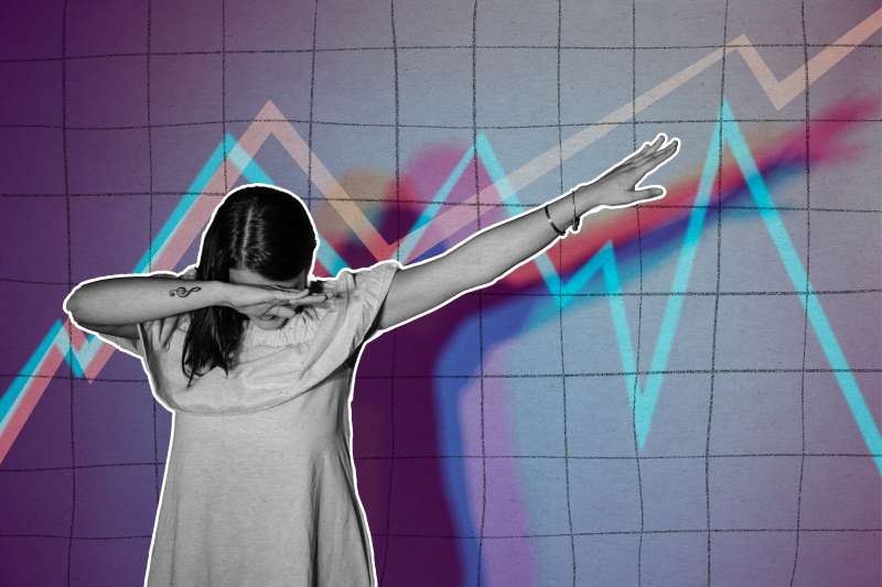 Young woman does a dance move in front of some stock market graphs