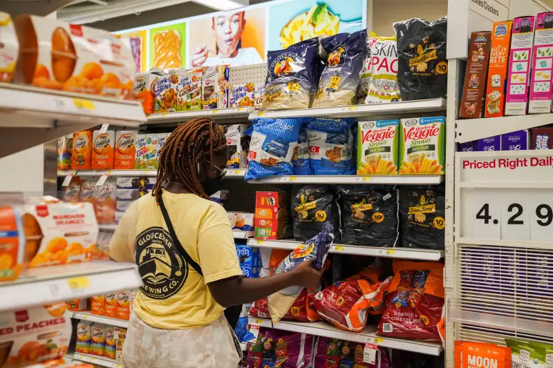 A woman picks groceries from a supermarket aisle