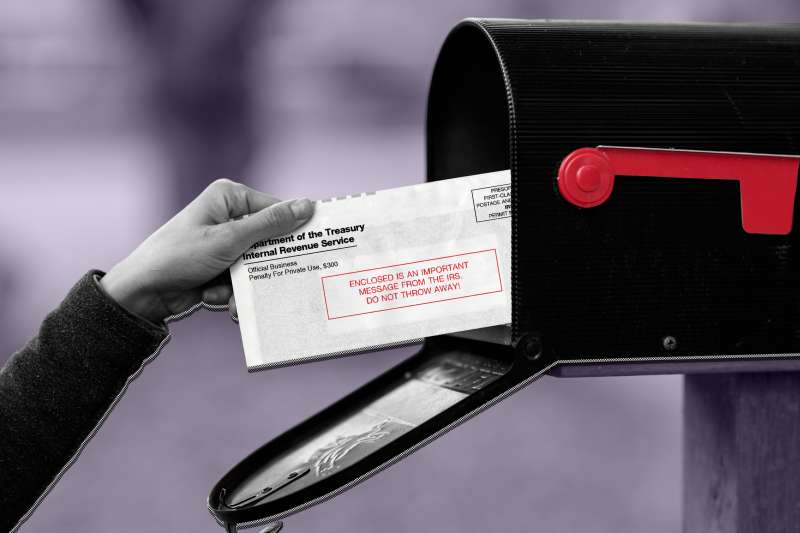 Close-up of a hand taking out a letter from the IRS from their mailbox