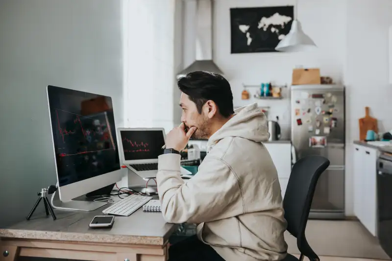 Man studying stock market charts on his personal computer at home