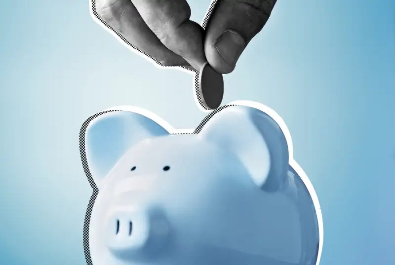 Close up view of a hand placing a coin into a piggy bank