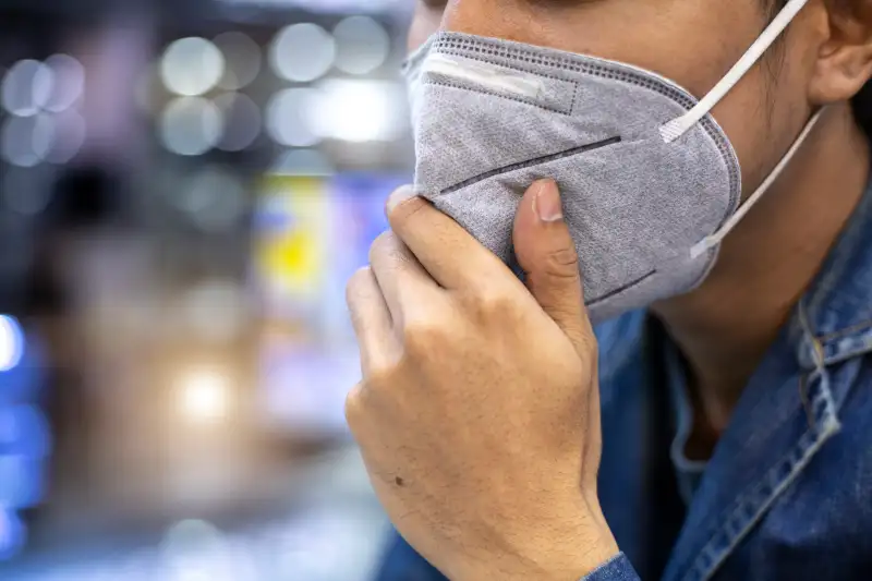 Close up of a man using a face mask in a city