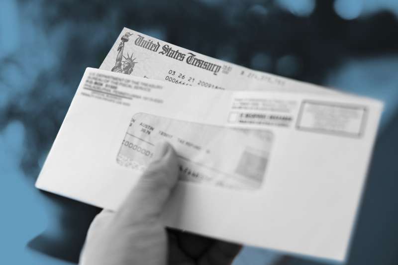 Hand holds an envelope with a US Stimulus Check inside