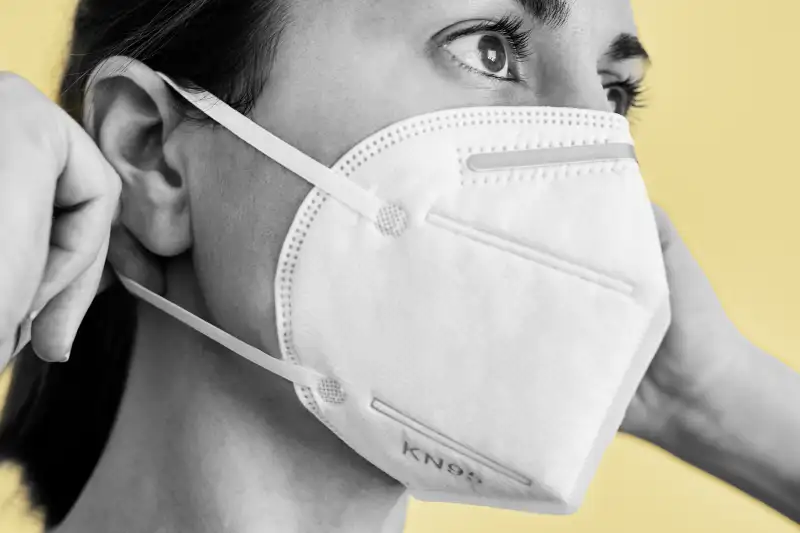 Close-up of a woman putting on a KN95 face mask