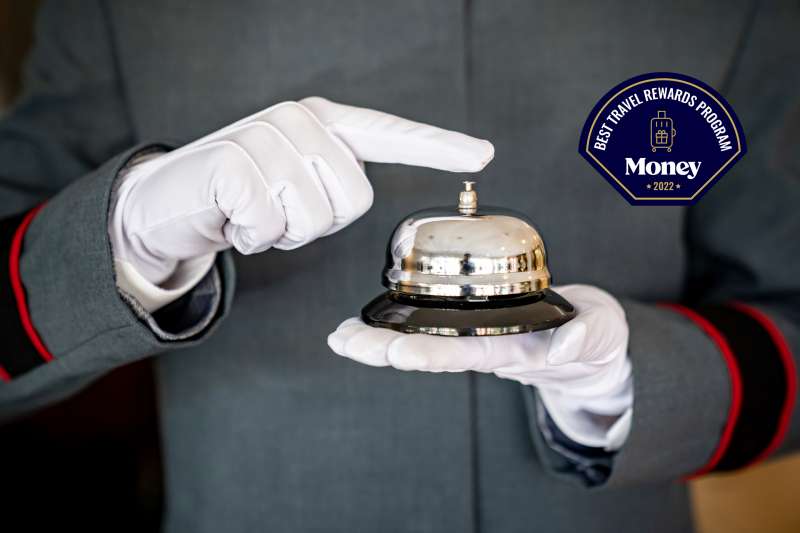 Close-up on a bellhop working at a hotel holding a service bell wearing a uniform and gloves