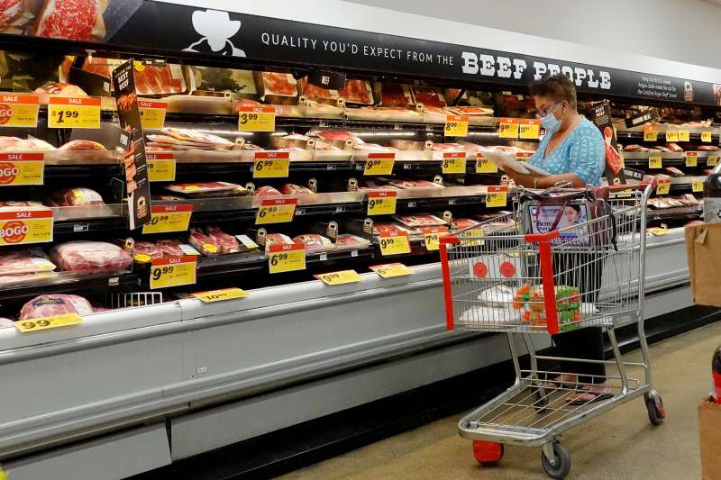 A woman looking at meat prices at a supermarket. The Labor Department announced that consumer prices jumped 7.5% last month