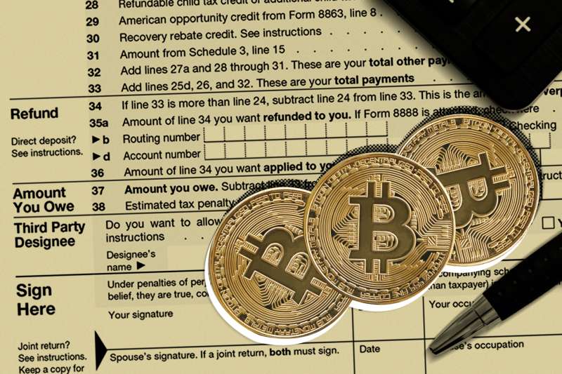 Three bitcoins laying on top of a 1040 Tax Return Form