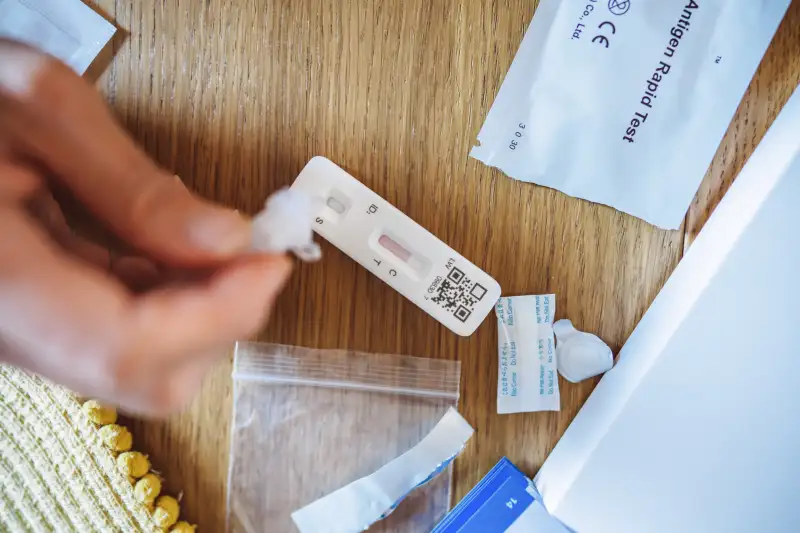 Close-up of a hand squeezing the sample liquid on a test strip for a Covid-19 rapid self test at home