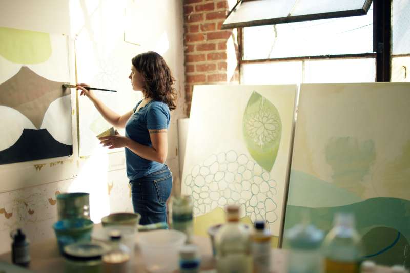 Female artist painting on canvas inside her Brooklyn apartment