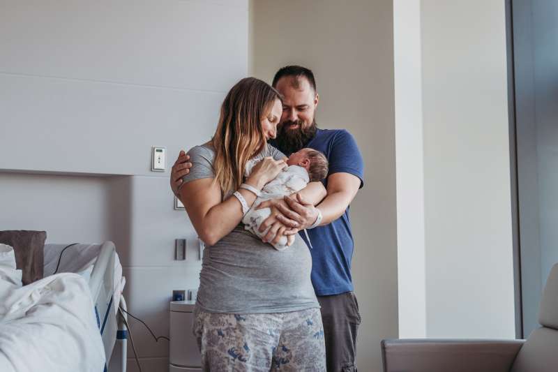 Young couple holding their new born baby in a hospital room