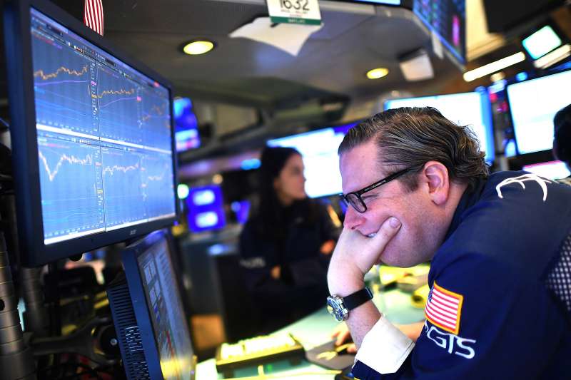 Man stares at a stock ticker graph with a worried face