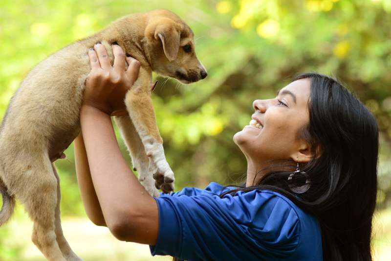 Woman happily holds up a puppy she just adopted
