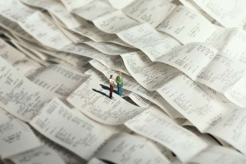 Photo-Illustration of a toy figure of a couple standing in a sea of receipts