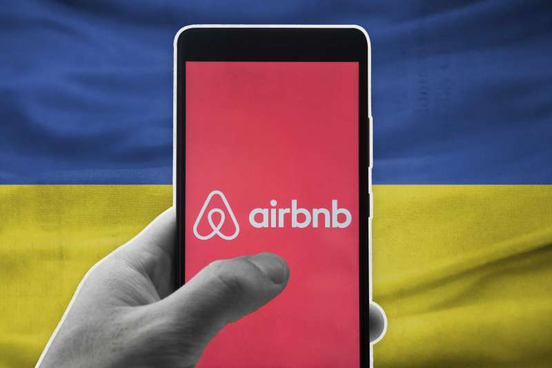 Smart Phone With AirBnB On Screen In Front Of Uraine Flag