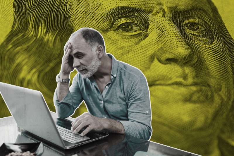 Worried Man In Front Of Laptop With Large Portrait Of Benjamin Franklin Behind Him