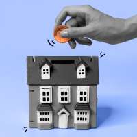 A hand inserting a penny into a house shaped coin bank.