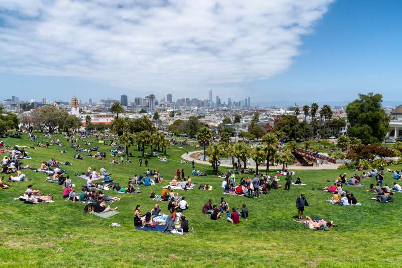 Multiple people sitting on the grass at Dolores Park in San Francisco